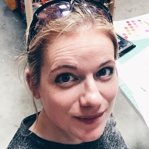 Kerri in the warehouse, sunglasses pushed up on her head, a cutting table behind her