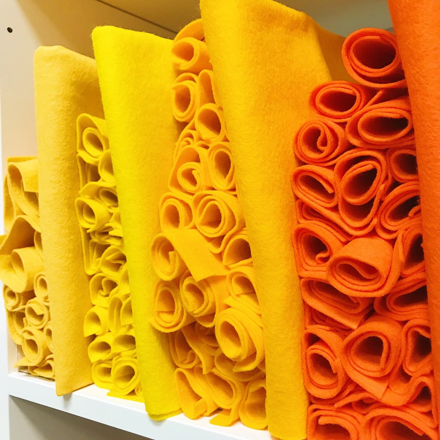 Warehouse shelves stacked with rolled felt in yellows, golds and oranges.