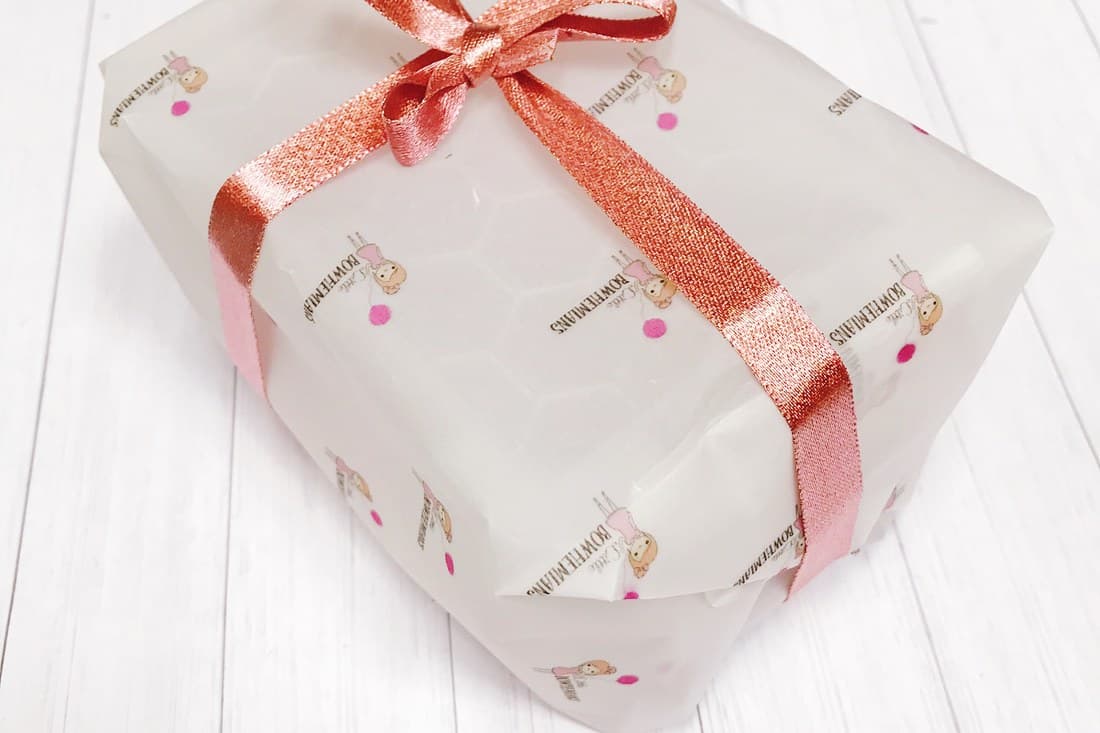 A parcel wrapped in Bowtiemums tissue paper and tied with a copper ribbon, ready to post